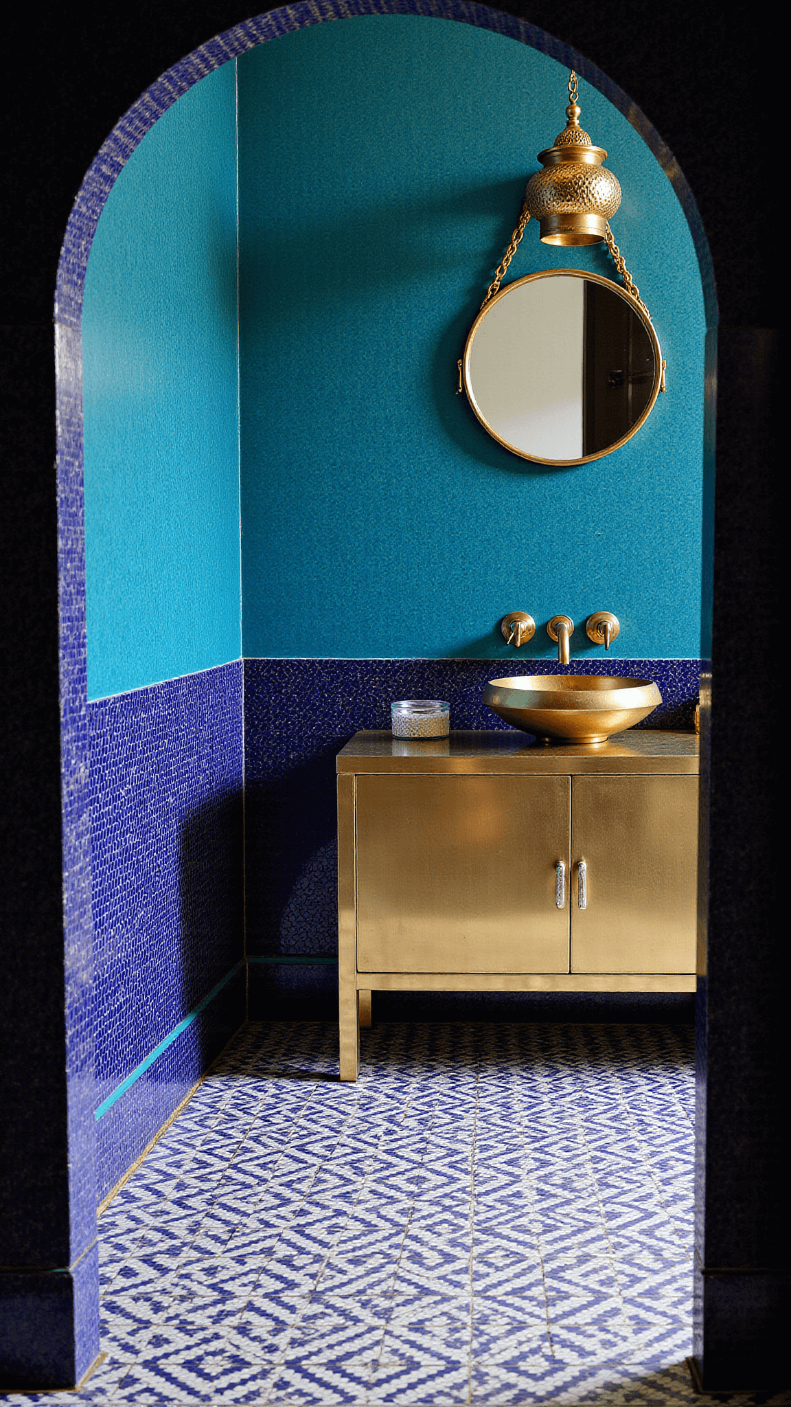 Overhead shot of a bold Moroccan-styled bathroom with jewel-toned zellige tiles, geometric cement floor, hammered brass vanity and dramatic accent lighting.