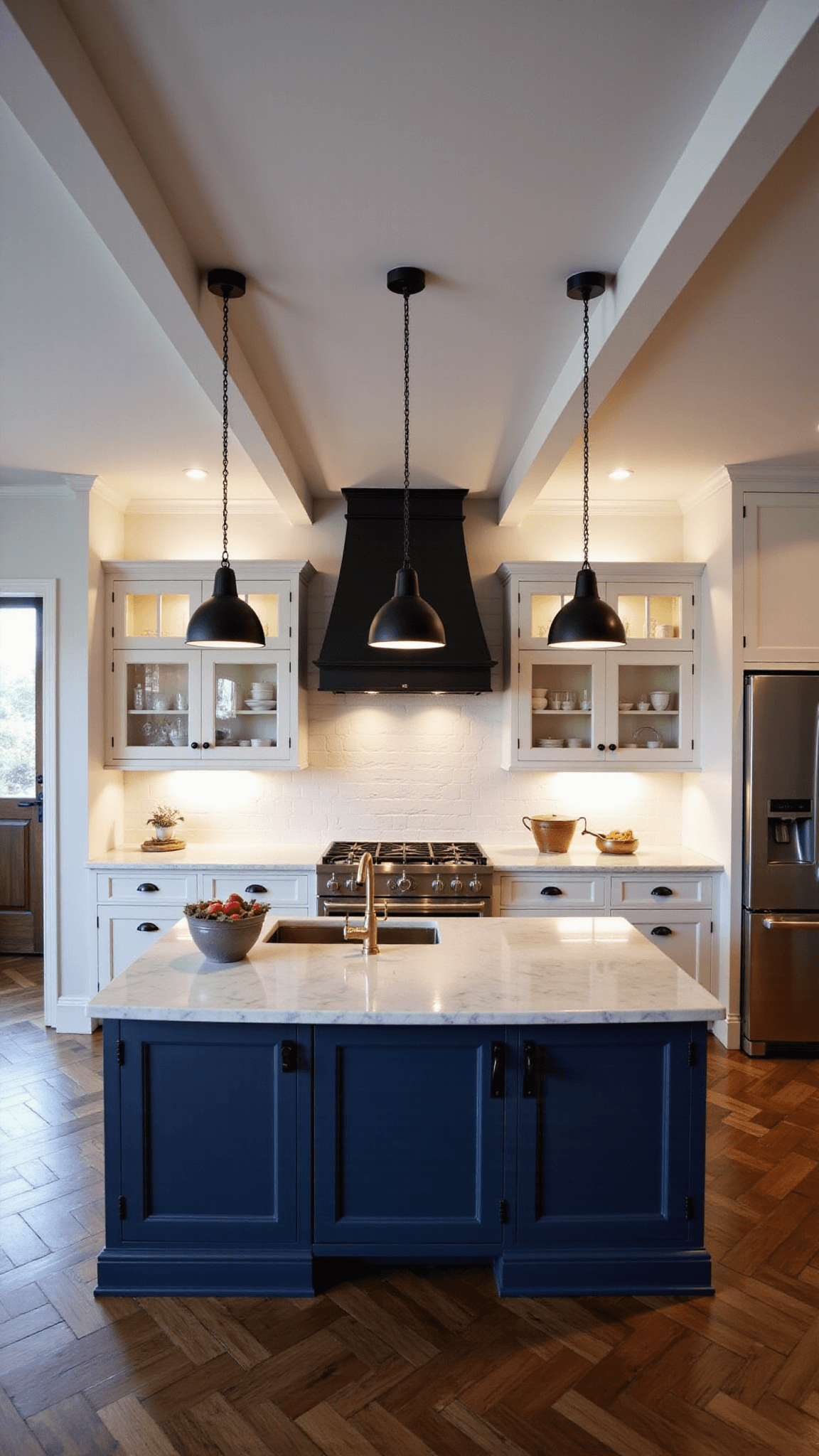 Overhead view of a spacious modern farmhouse kitchen with a large navy blue island, herringbone wood floors, and cream cabinets, under soft, moody lighting at dusk.